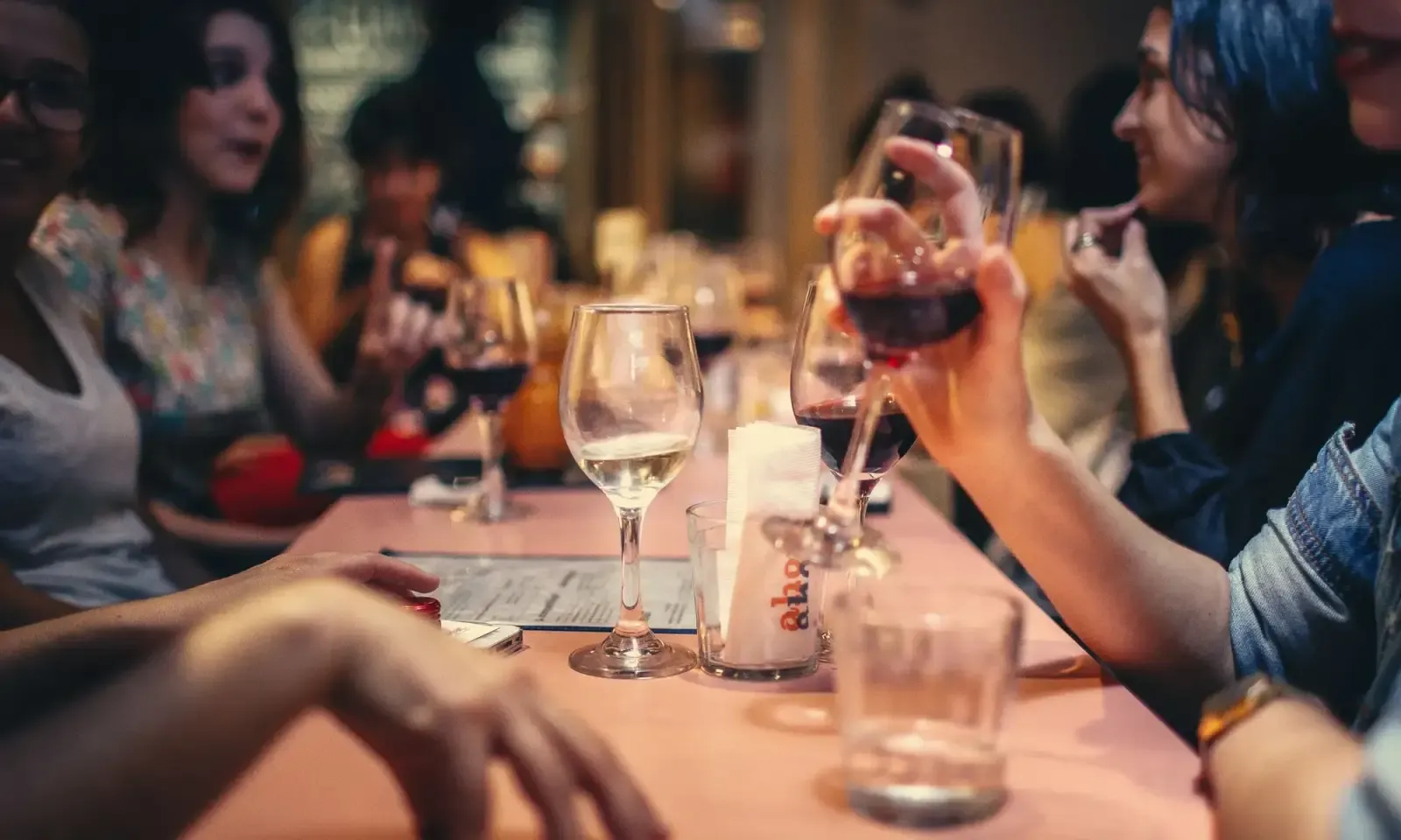 A dining table set with glasses of water and wine in soft evening light.